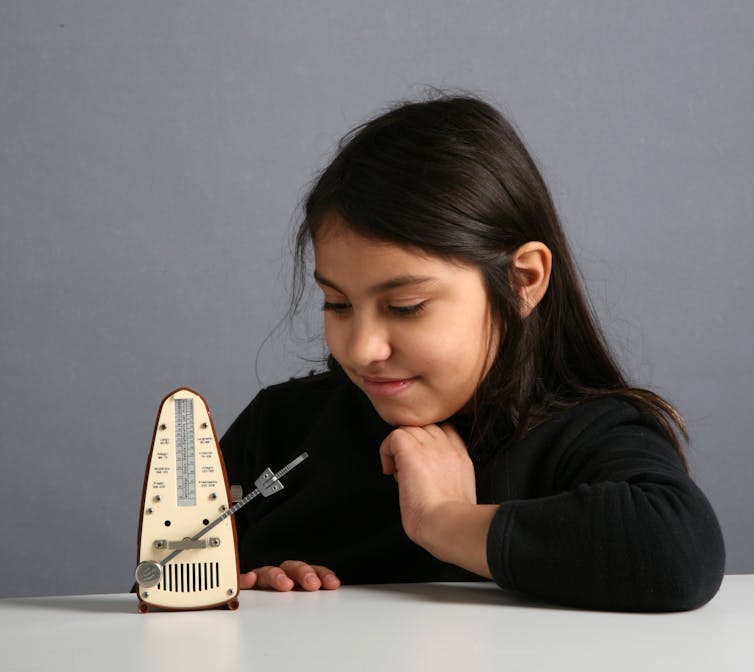 a girl looks at a metronome on a table