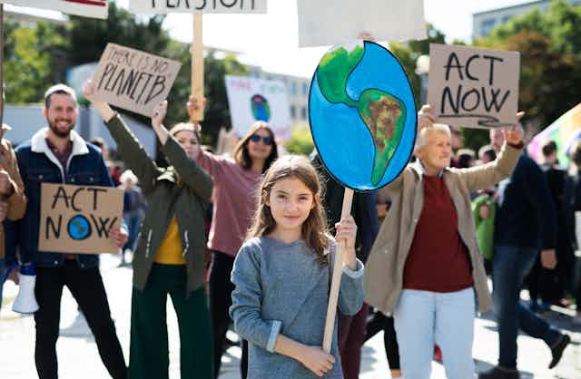 A young girl holding a placard of the Earth in a climate protest.