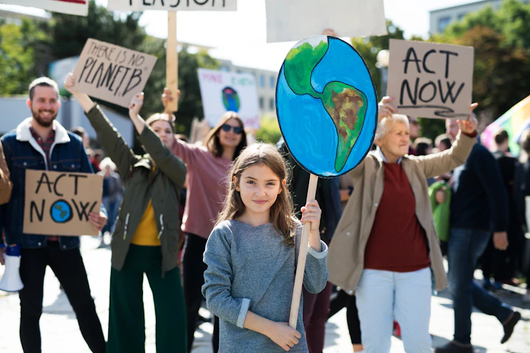 A young girl holding a placard of the Earth in a climate protest.
