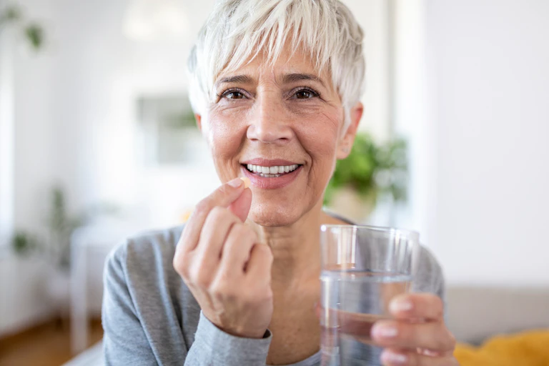 Woman with grey hair taking a pill