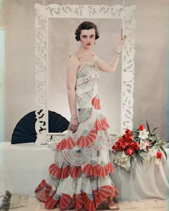 Margaret Sweeny in a frilly white and red dress, stands holding a frame.