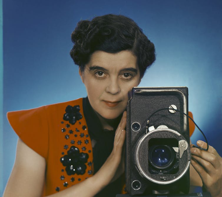 Yevonde holding a large camera.