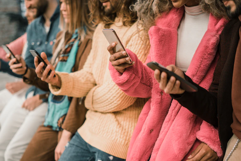 A group of people in a row looking at their phones.