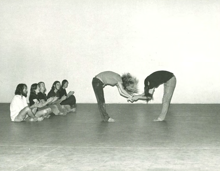 Five students clap while two bow towards each other.