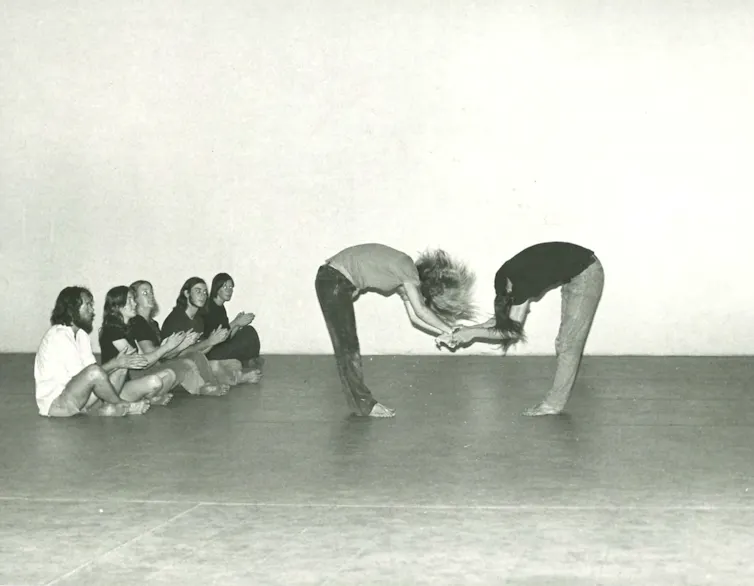 Five students clap while two bow towards each other.