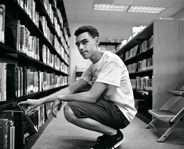 A young man gets a book from a library shelf