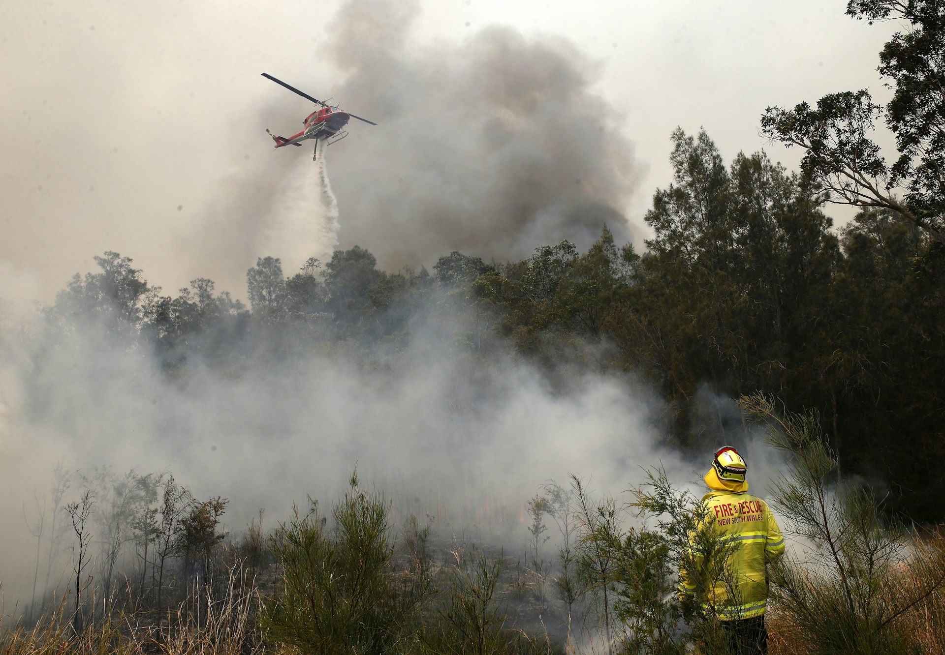 helicopter dumps water on burning bush