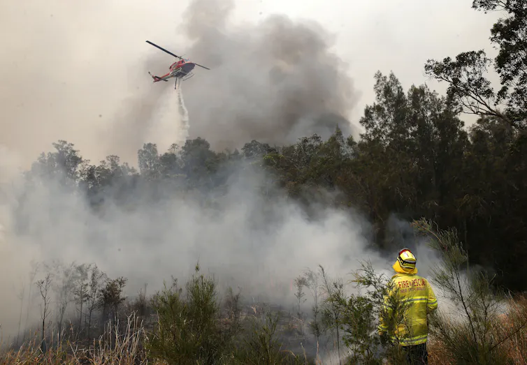 helicopter dumps water on burning bush