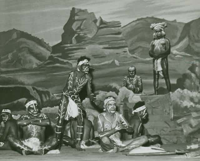 Seven Aboriginal men in traditional dress on a stage