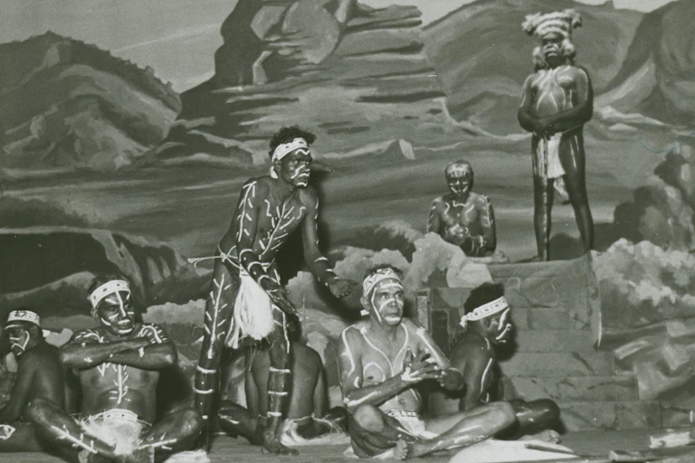 Seven Aboriginal men in traditional dress on a stage