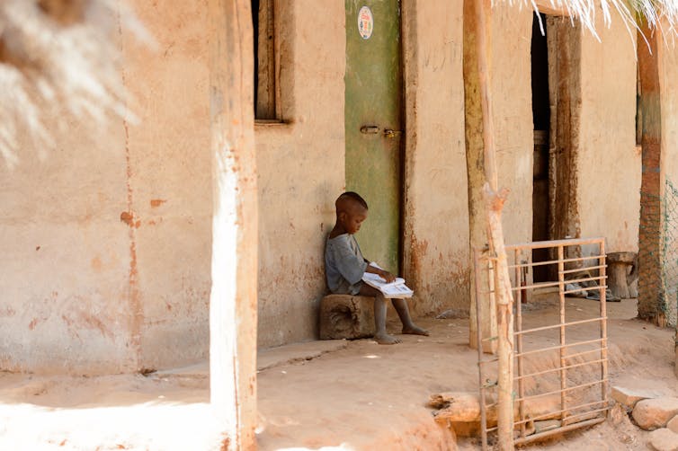 Boy reads near his house in a village of the Canhabaque island.