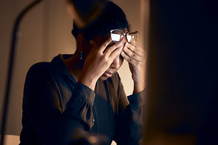 A young woman with her head in her hands, looking at a computer screen