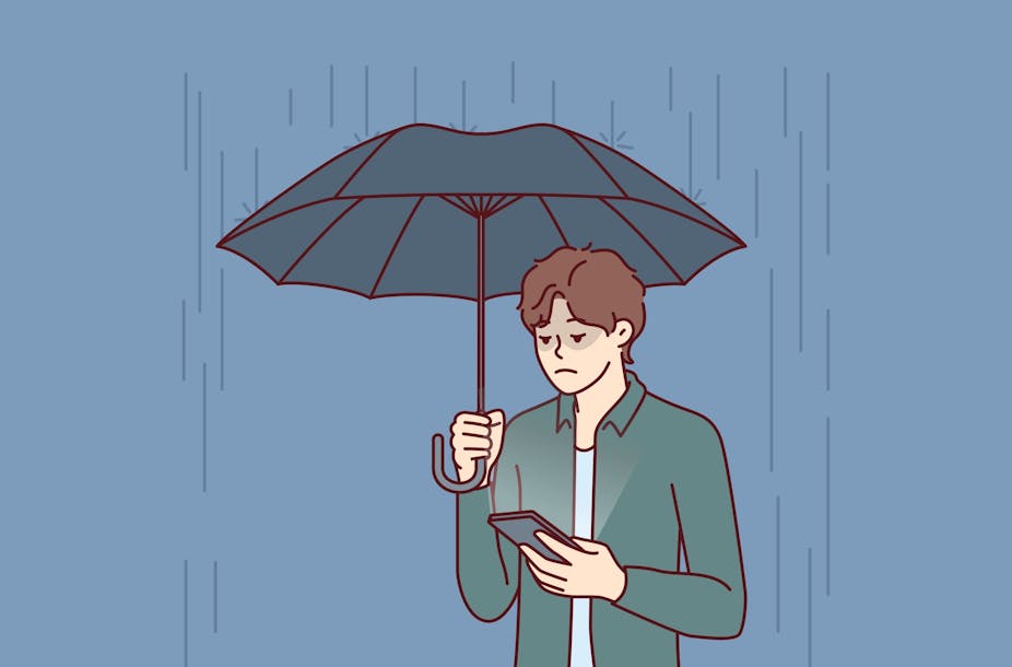 Homme sous la pluie qui attend une réponse en regardant son smartphone