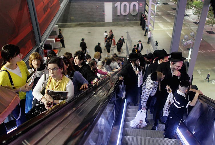 Men and women ride separate escalators to their designated seating sections as Orthodox Jews gather during a 2012 event to celebrate religious study in New Jersey. Mario Tama/Getty Images