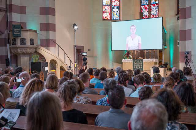 A church congregation listens to a sermon delivered by a Chatbot