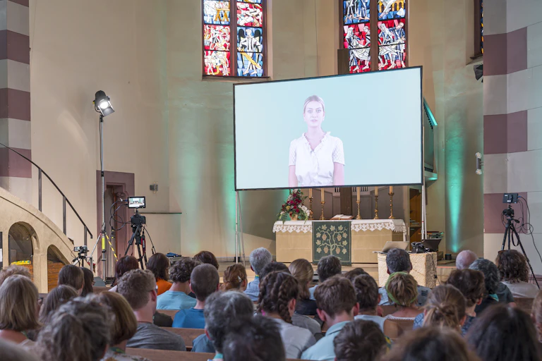 A church congregation listens to a sermon delivered by a Chatbot