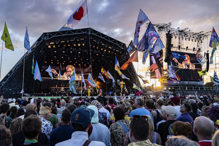 People in a large crowd face a stage where a man performs.