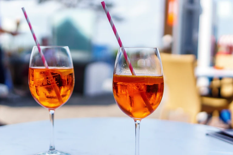 Gros plan sur deux verres de spritz, avec pailles.