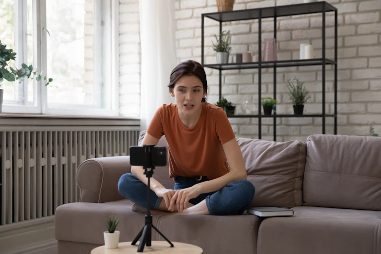A young woman sitting on a couch and talking to a camera