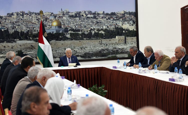 A group of men and one woman sit around a large conference table.