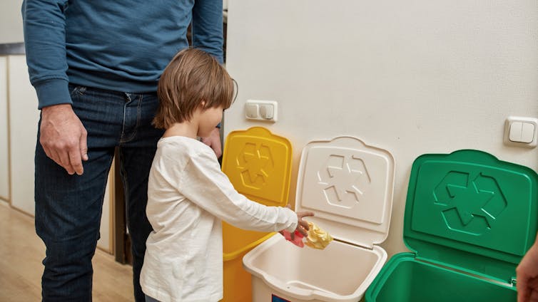 A child throws paper in a recycling bin.