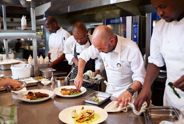 A number of black chefs in a nice commercial kitchen.