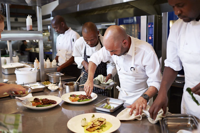 A number of black chefs in a nice commercial kitchen.