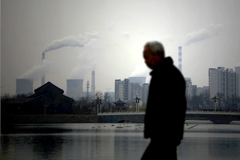 man walks past smoke stacks
