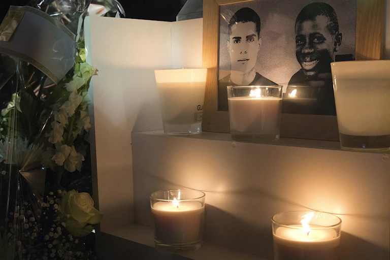 Une photo prise le 27 octobre 2015 à Clichy-sous-Bois montre des fleurs et des bougies placées près d'une plaque érigée à la mémoire de Bouna Traore (R) et Zyed Benna, deux adolescents locaux qui sont morts en fuyant la police le 27 octobre 2005.