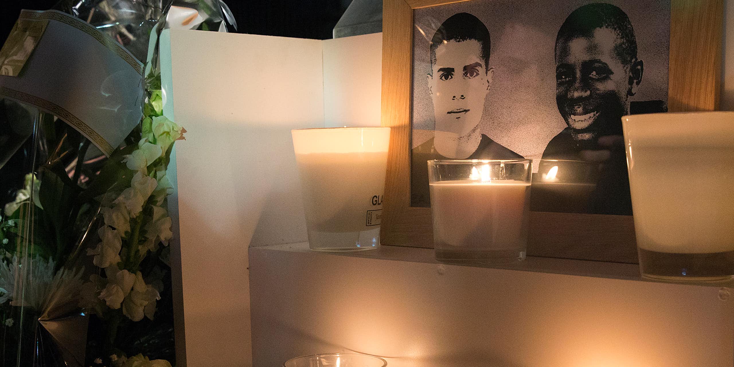 Une photo prise le 27 octobre 2015 à Clichy-sous-Bois montre des fleurs et des bougies placées près d'une plaque érigée à la mémoire de Bouna Traore (R) et Zyed Benna, deux adolescents locaux qui sont morts en fuyant la police le 27 octobre 2005.