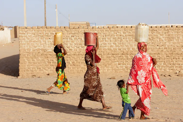 Sudanese women carrying watger pots on their heads in Karima.