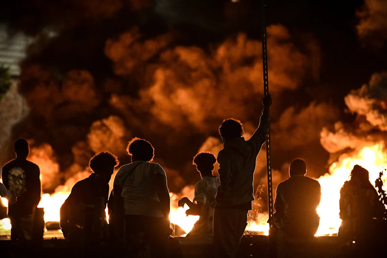 Des personnes regardent des pneus en feu bloquant une rue à Bordeaux, dans le sud-ouest de la France, le 29 juin 2023, lors d'émeutes et d'incidents dans tout le pays après le meurtre d'un jeune homme de 17 ans par un policier .