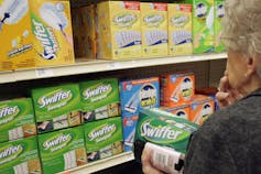 A woman choosing from Swiffer products in a store aisle.