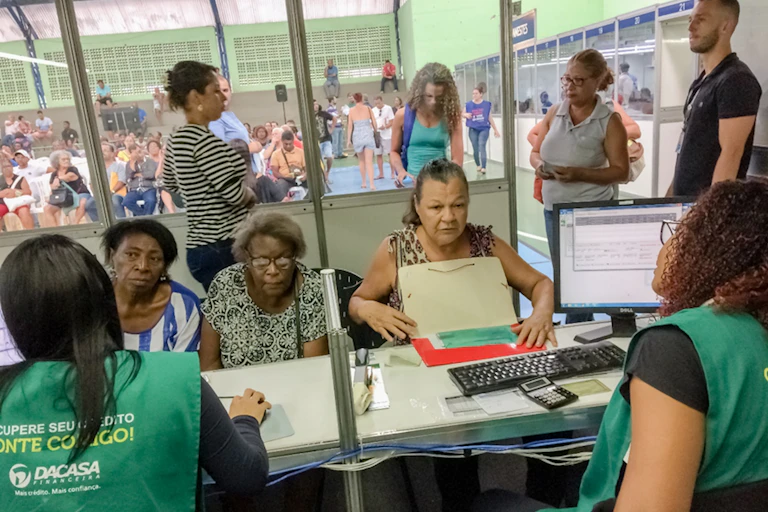 Deudoras (en su mayoría mujeres mayores y racializadas) y cobradoras (de verde), en Vitoria (Espirito Santo, Brasil) durante una feria de renegociación de deudas celebrada en diciembre de 2019.