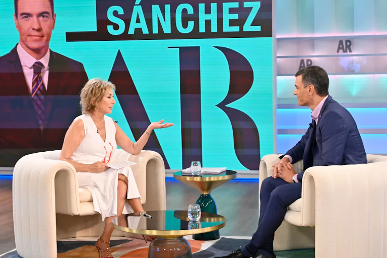 Una mujer habla con un hombre en un plató de televisión.