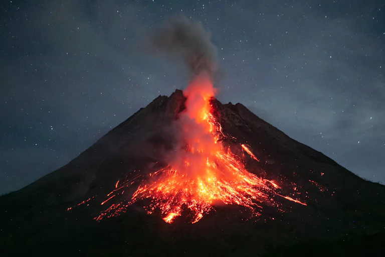 Bright orange lava runs down the side of a volcano at dusk.