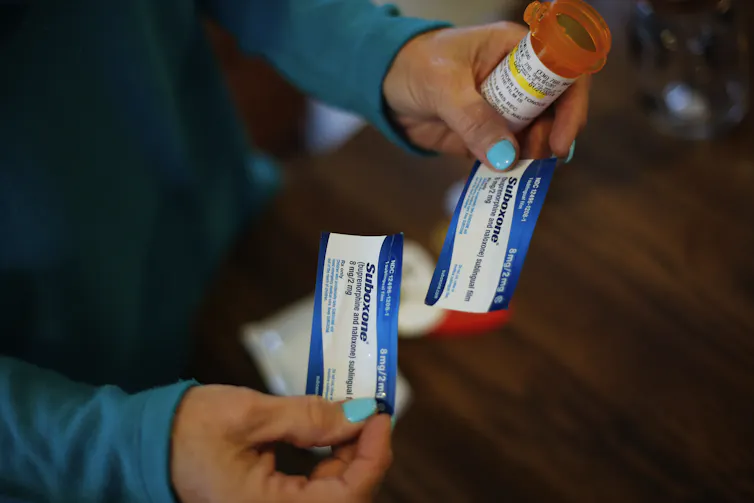 Close-up photo of a woman's hands holding two small packages labeled Suboxone.
