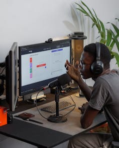 Un hombre habla por un micrófono con los auriculares puestos sentado delante de un ordenador