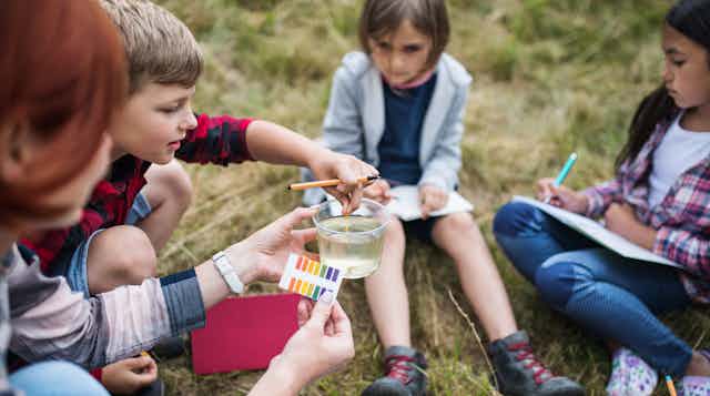 Children testing pH levels in river or lake water