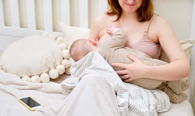 woman breastfeeds baby, looks downcast