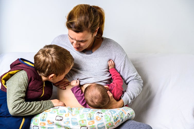 woman breastfeeding baby and older child at the same time