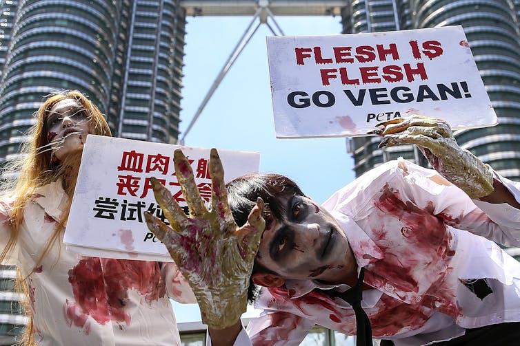 protesters with sign reading 'Flesh is flesh, go vegan'