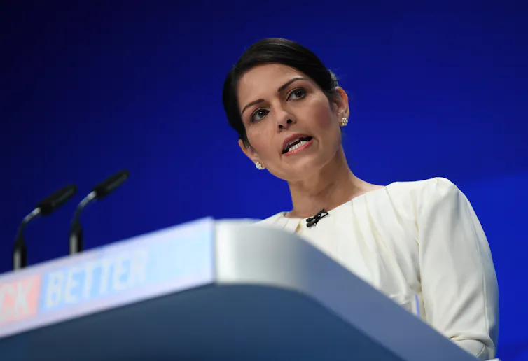 Priti Patel speaking at a podium