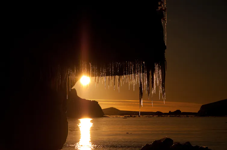 Sunset seen through the icicles hanging from an ice shelf around Antarctica.