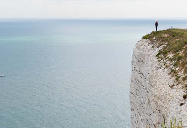 A woman standing on the edge of the cliffs at Eastbourne. 