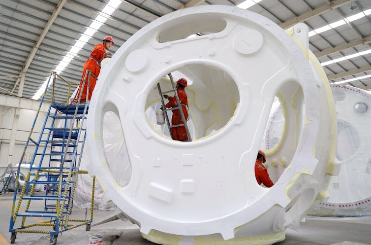 Two workers making a wind turbine.