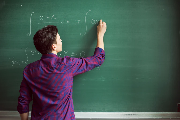 A student completing a math equation on a chalkboard.