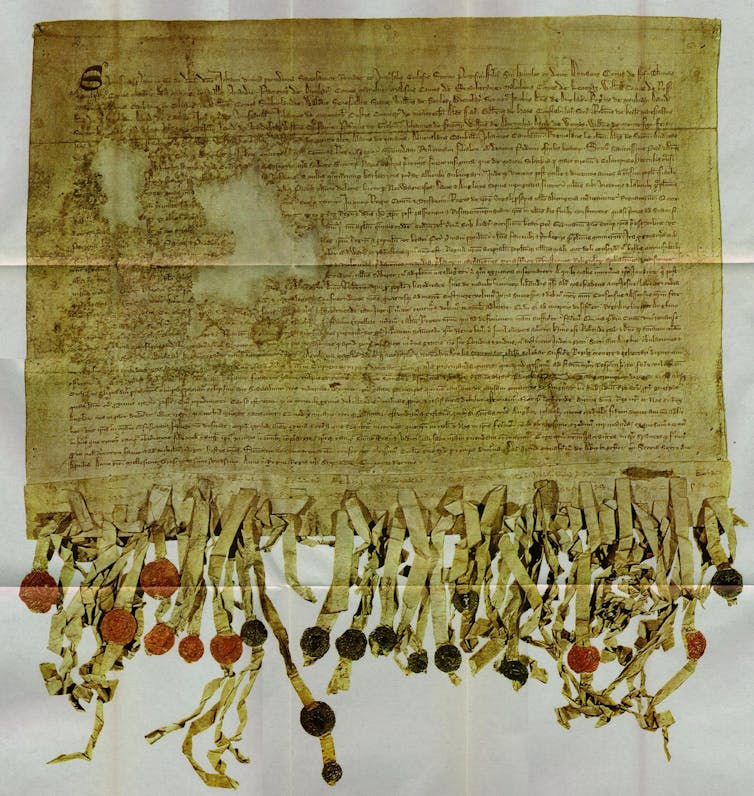 A very fragile old document, the Declaration of Arbroath, on faded yellowed paper.
