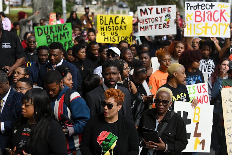 Demonstrators hold signs that read 'Protect Black history' and 'Black history is US history'