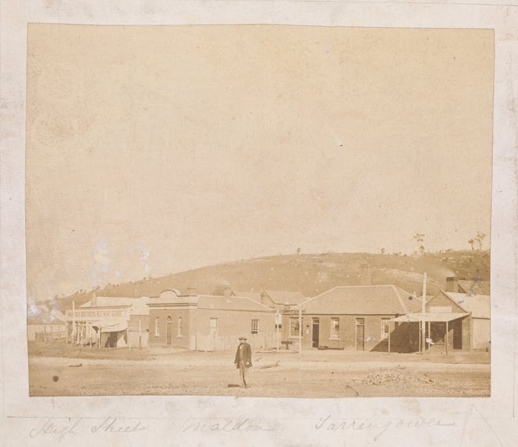 Sepia photograph: one man, a few huts.